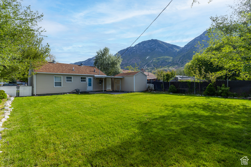 Back of house featuring a mountain view, a patio, and a gate