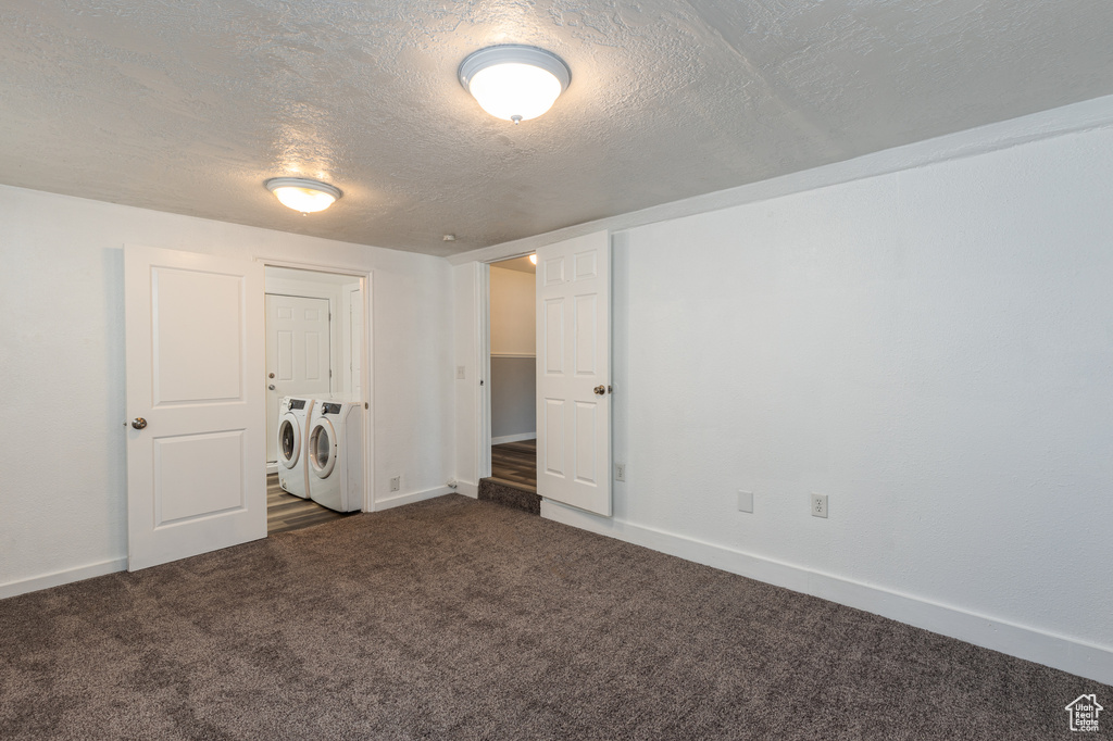 Unfurnished bedroom featuring washer and clothes dryer, carpet flooring, a textured ceiling, and baseboards