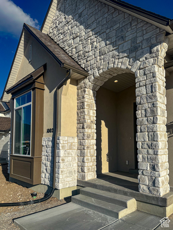 Entrance to property featuring stone siding and stucco siding