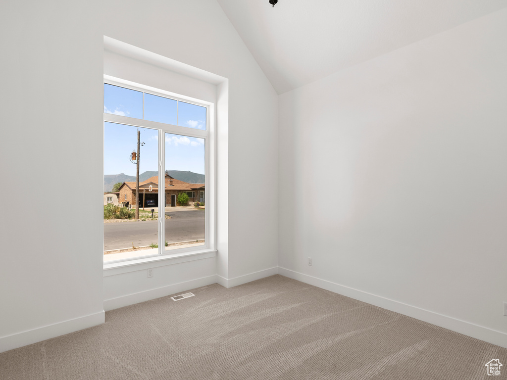 Spare room featuring light carpet and lofted ceiling