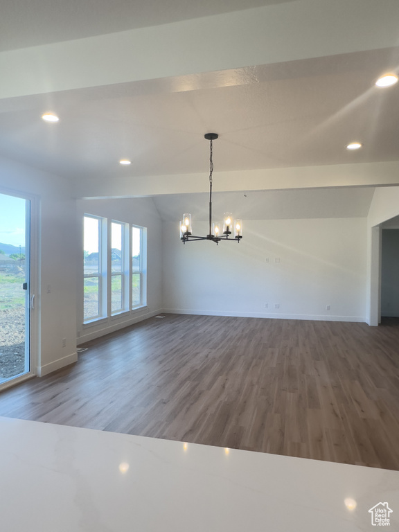 Unfurnished dining area with a chandelier, vaulted ceiling, wood finished floors, baseboards, and recessed lighting