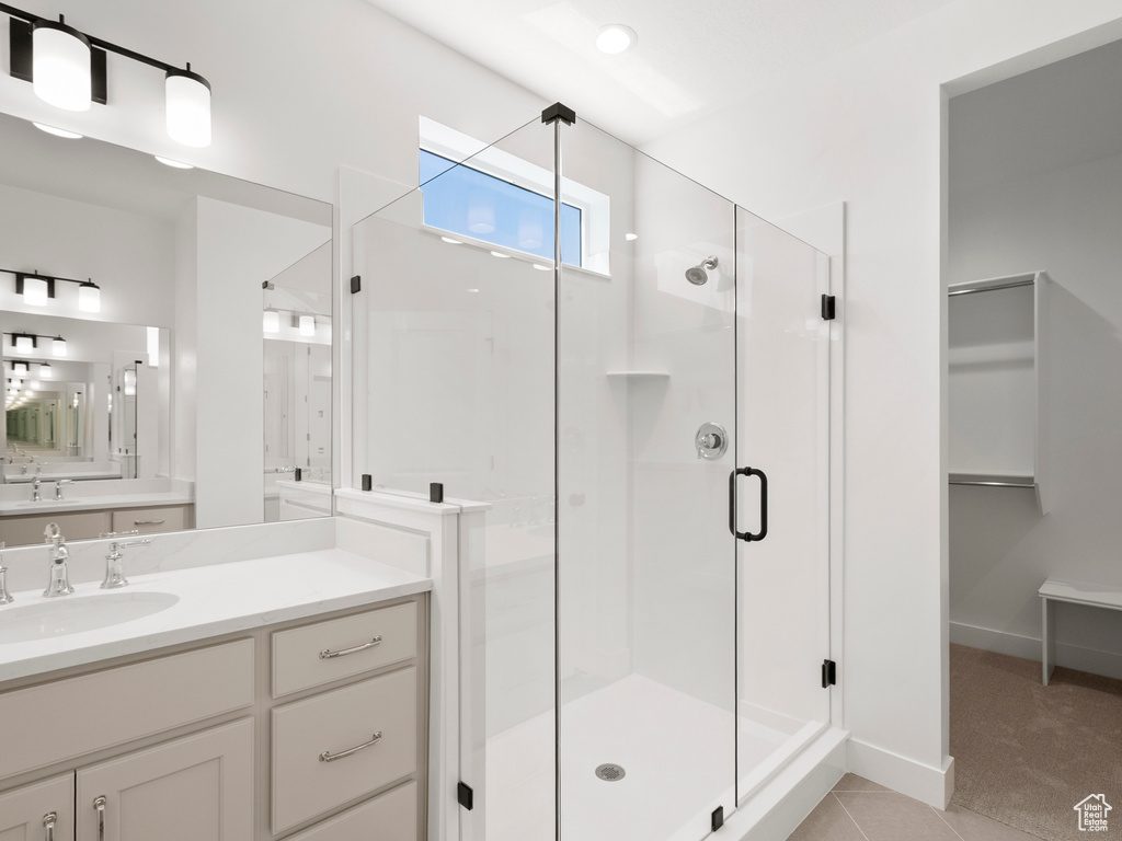 Full bath with a shower stall, vanity, a spacious closet, and tile patterned floors