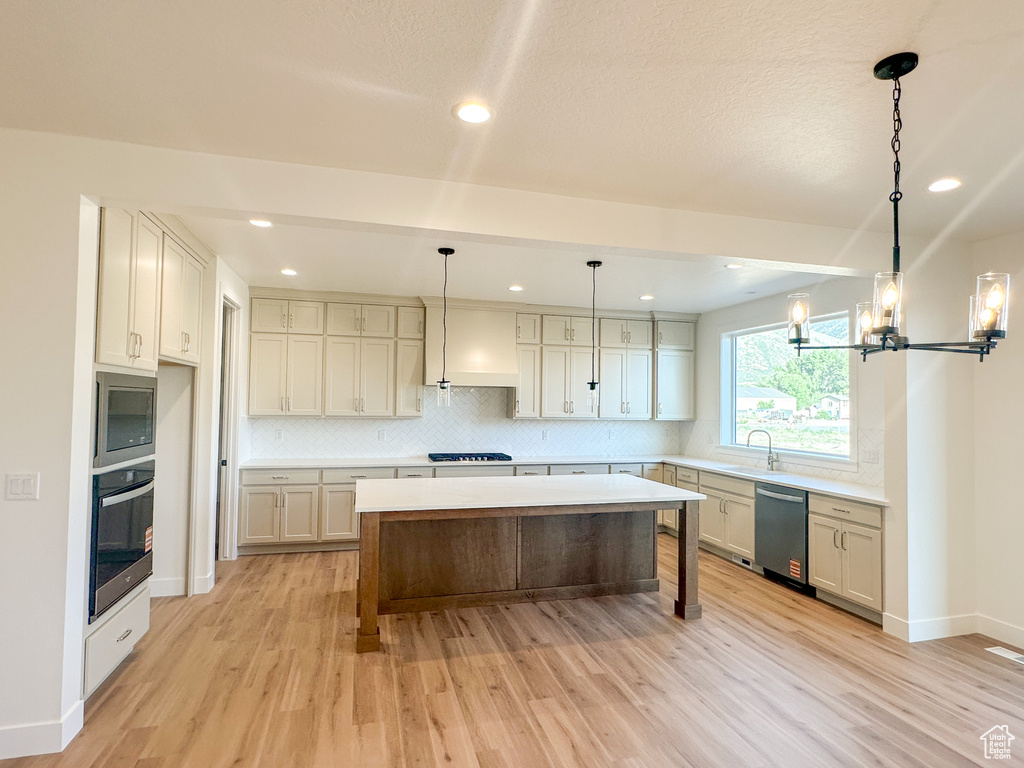 Kitchen with stainless steel appliances, light wood-type flooring, backsplash, a center island, and recessed lighting