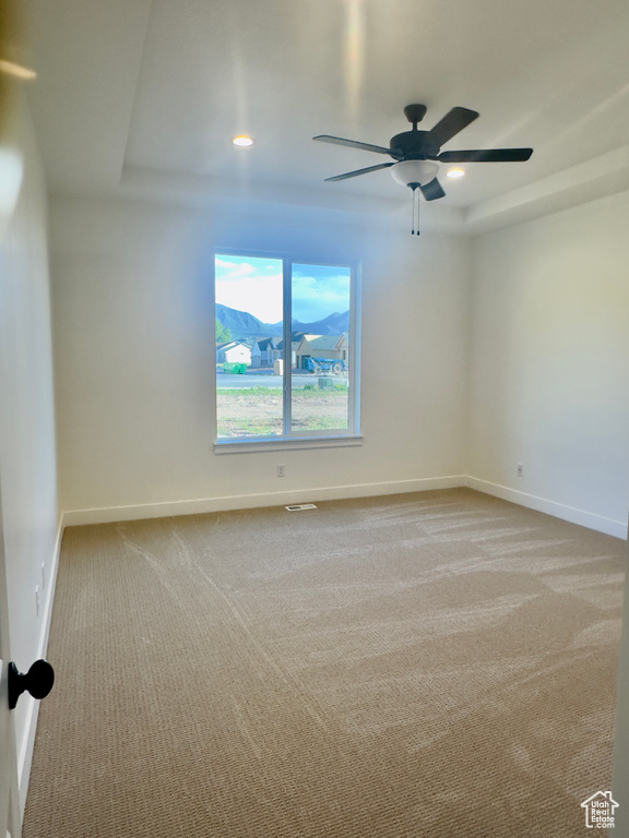 Carpeted spare room with baseboards, a raised ceiling, a ceiling fan, and recessed lighting