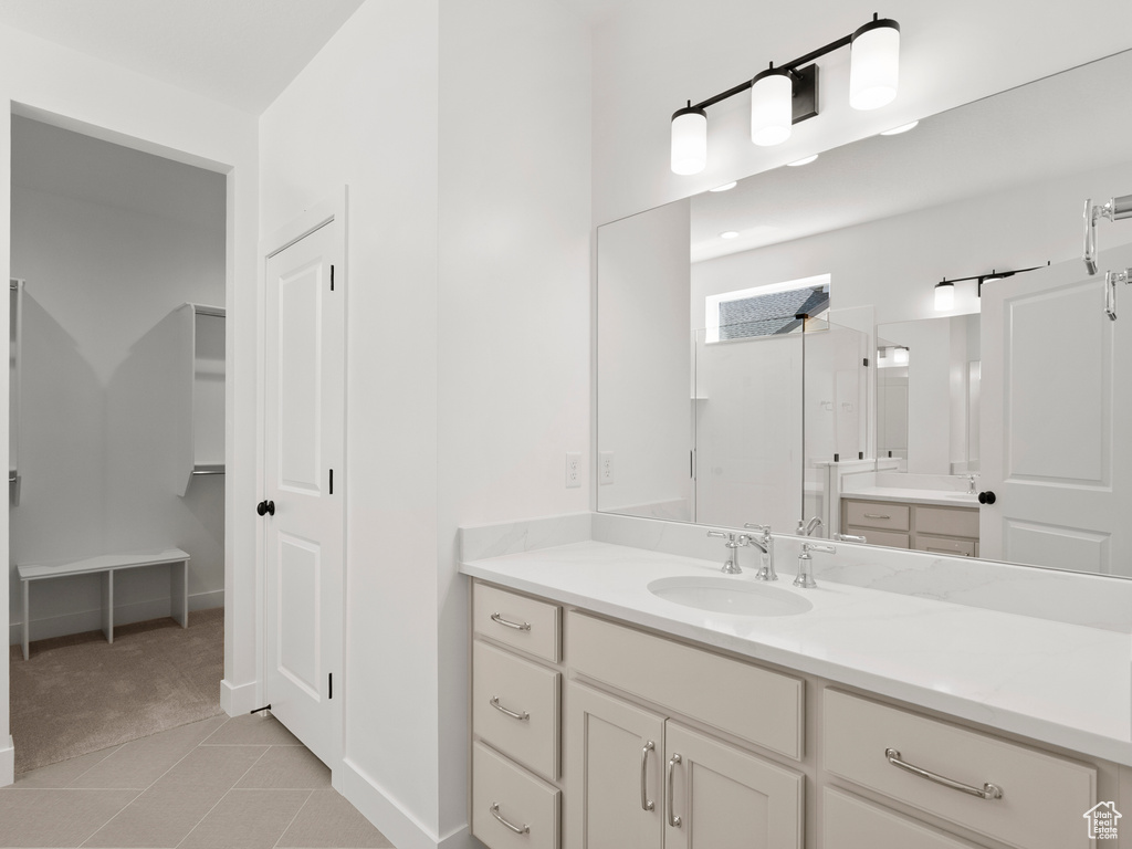 Full bath featuring vanity, a walk in shower, tile patterned flooring, and a spacious closet