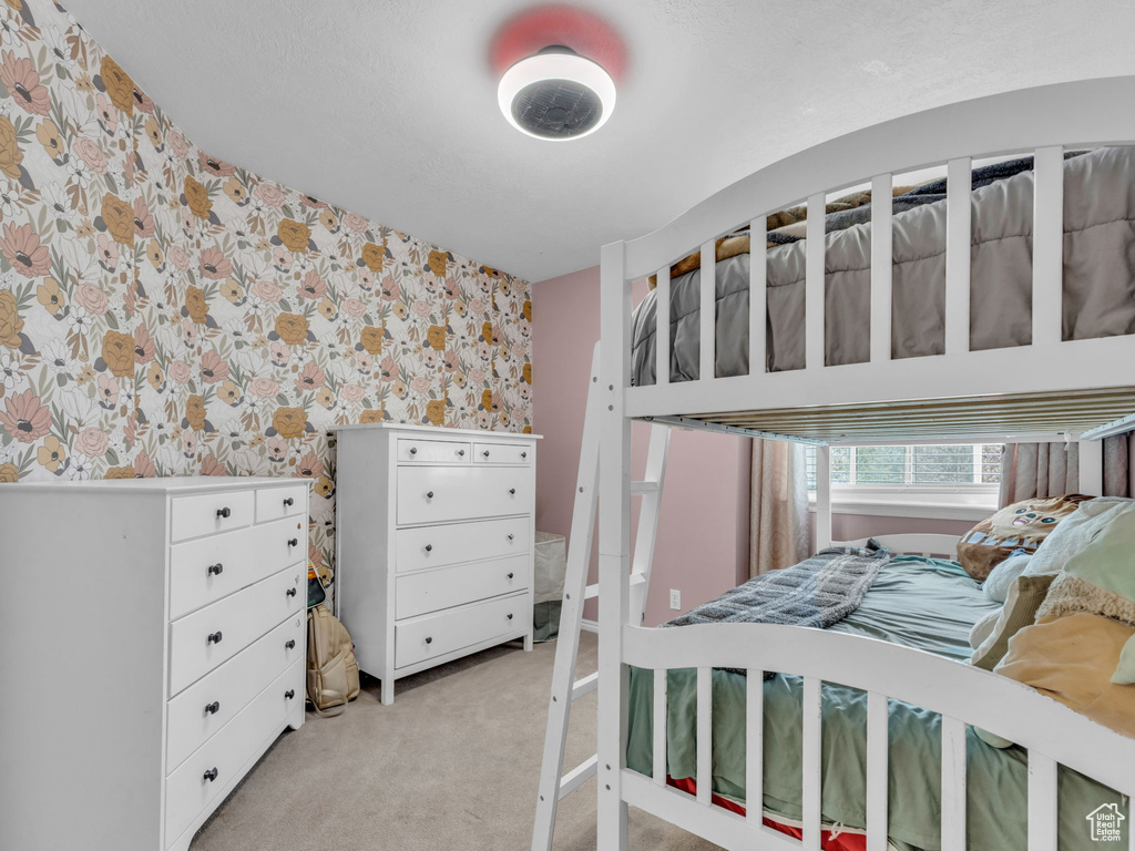 Bedroom with wallpapered walls and light colored carpet