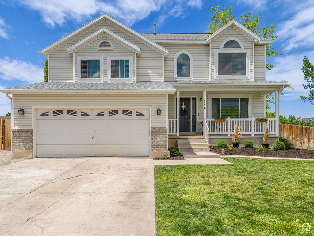 Traditional-style home featuring covered porch, driveway, a garage, and brick siding