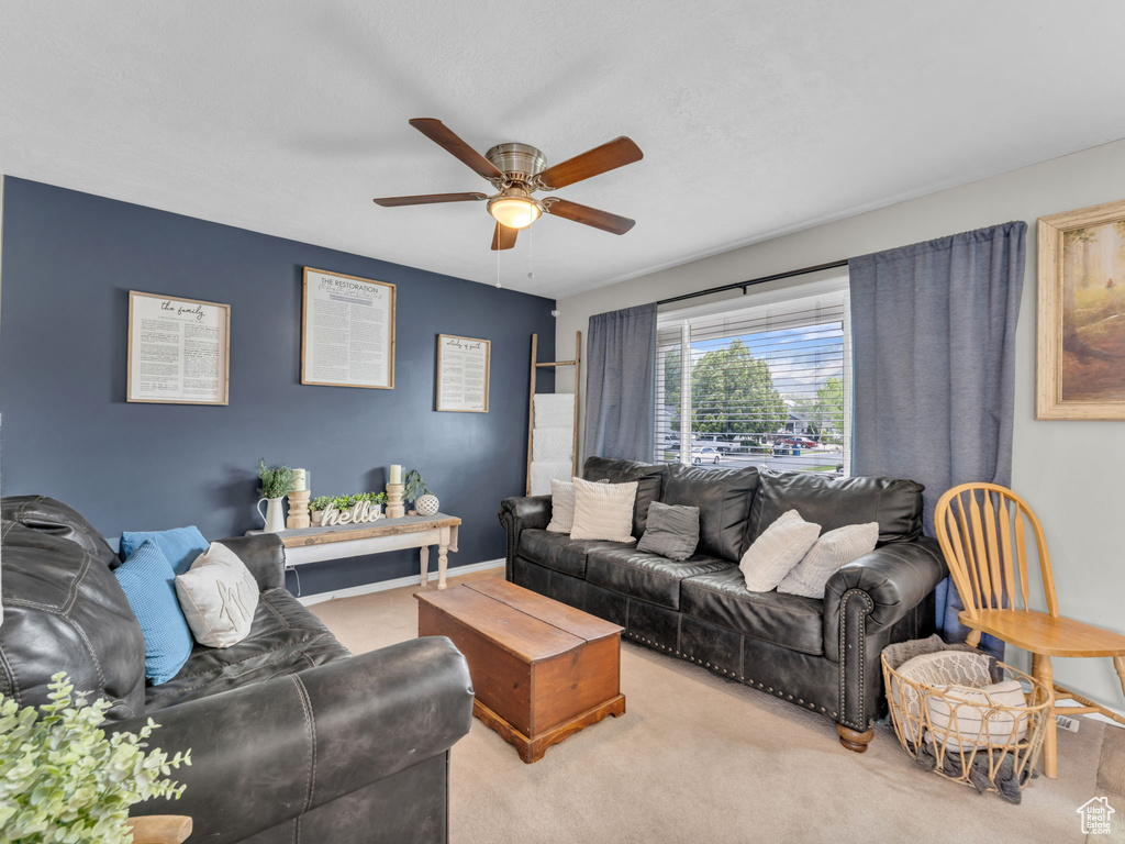 Carpeted living area with ceiling fan and baseboards
