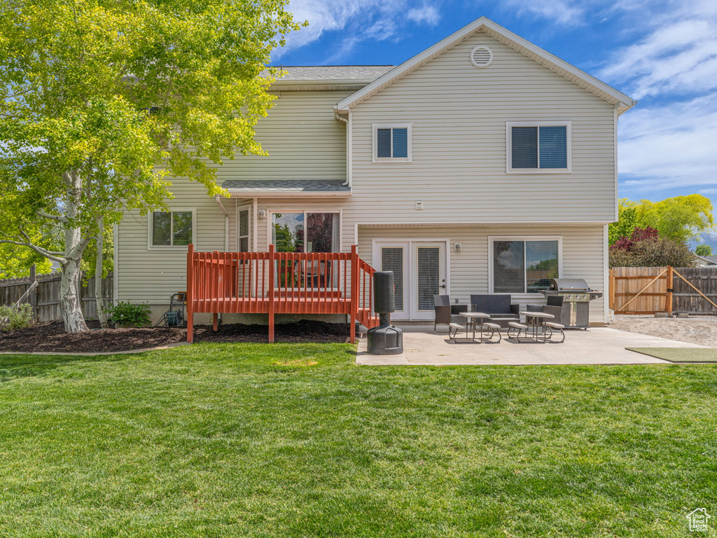 Back of property featuring a deck and a patio