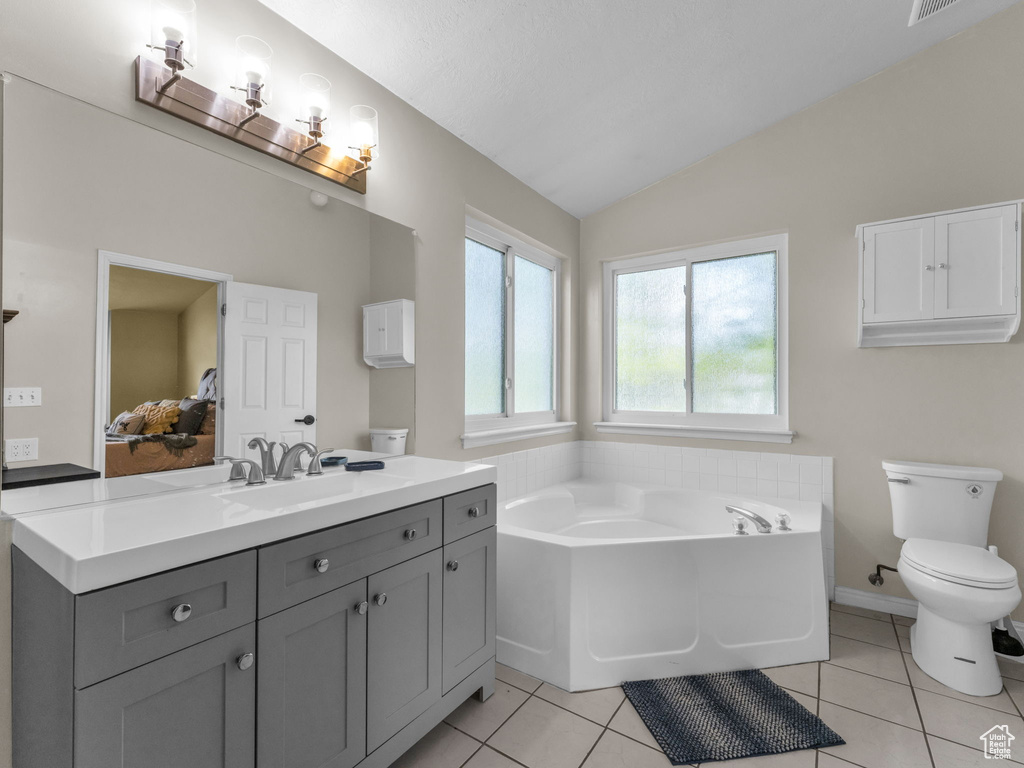 Ensuite bathroom featuring vanity, a bath, toilet, lofted ceiling, and tile patterned flooring