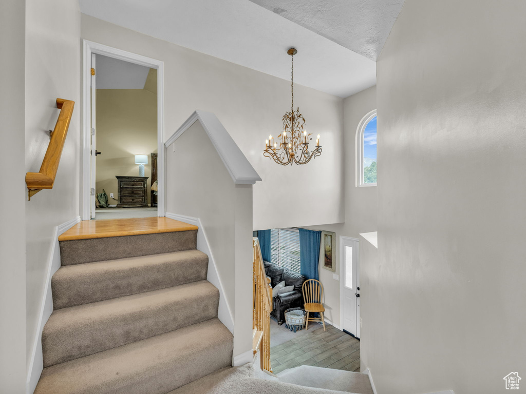Stairway featuring a chandelier, baseboards, and carpet flooring