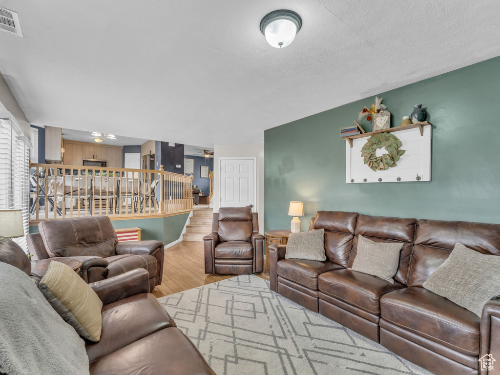 Living area with wood finished floors, stairs, a ceiling fan, and baseboards