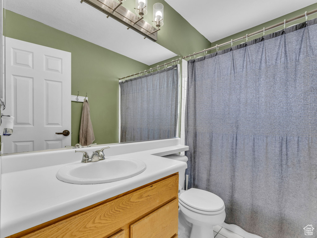 Bathroom with vanity, toilet, a chandelier, and tile patterned flooring