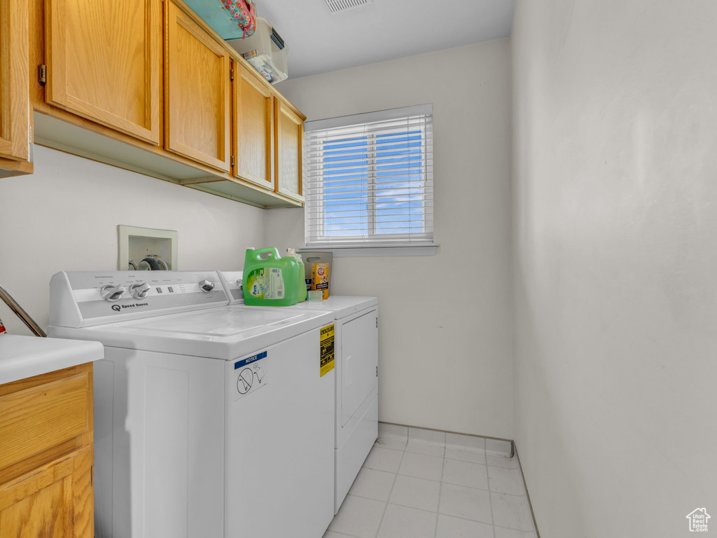Washroom featuring cabinet space, washing machine and dryer, and light tile patterned floors