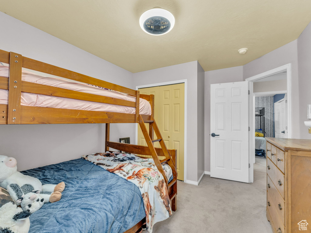 Bedroom featuring light colored carpet, baseboards, and a closet