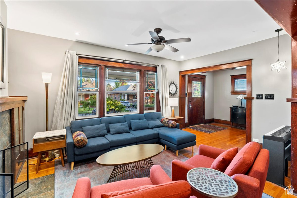 Living area with wood finished floors, a premium fireplace, a ceiling fan, and baseboards