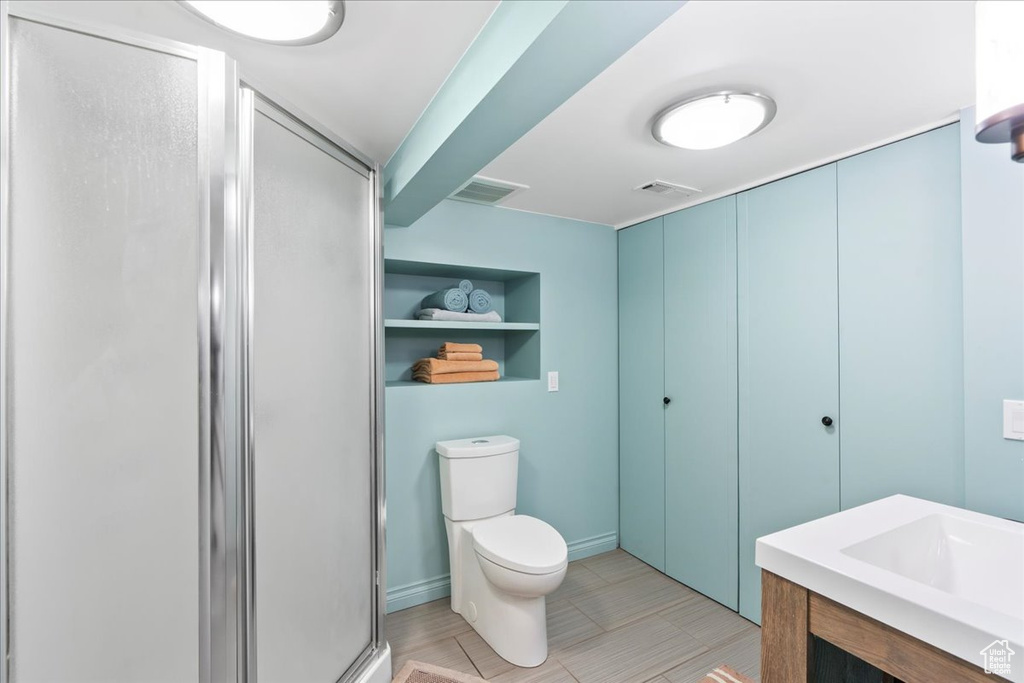 Bathroom with a stall shower, toilet, and built in shelves