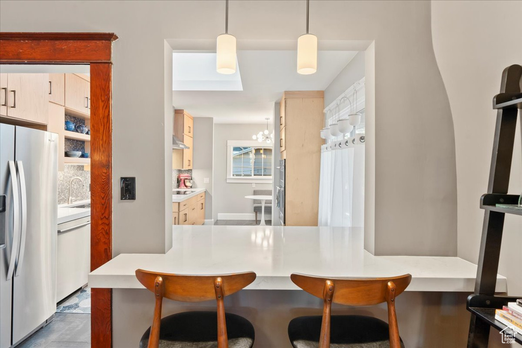 Kitchen with stainless steel fridge with ice dispenser, dishwasher, a breakfast bar, a sink, and a chandelier
