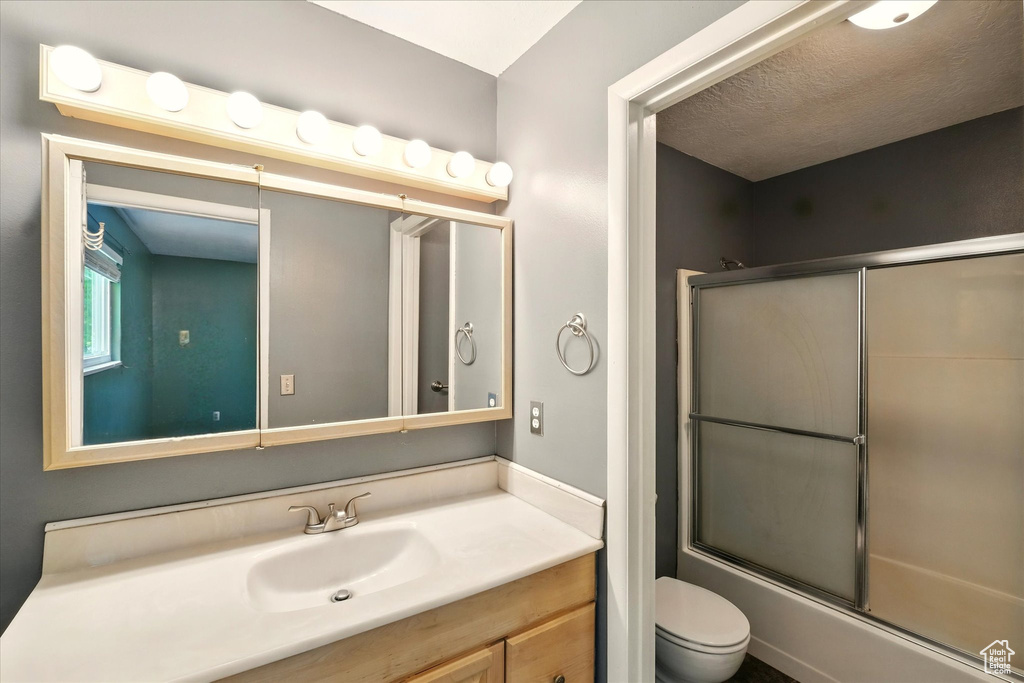 Full bath featuring toilet, vanity, and enclosed tub / shower combo