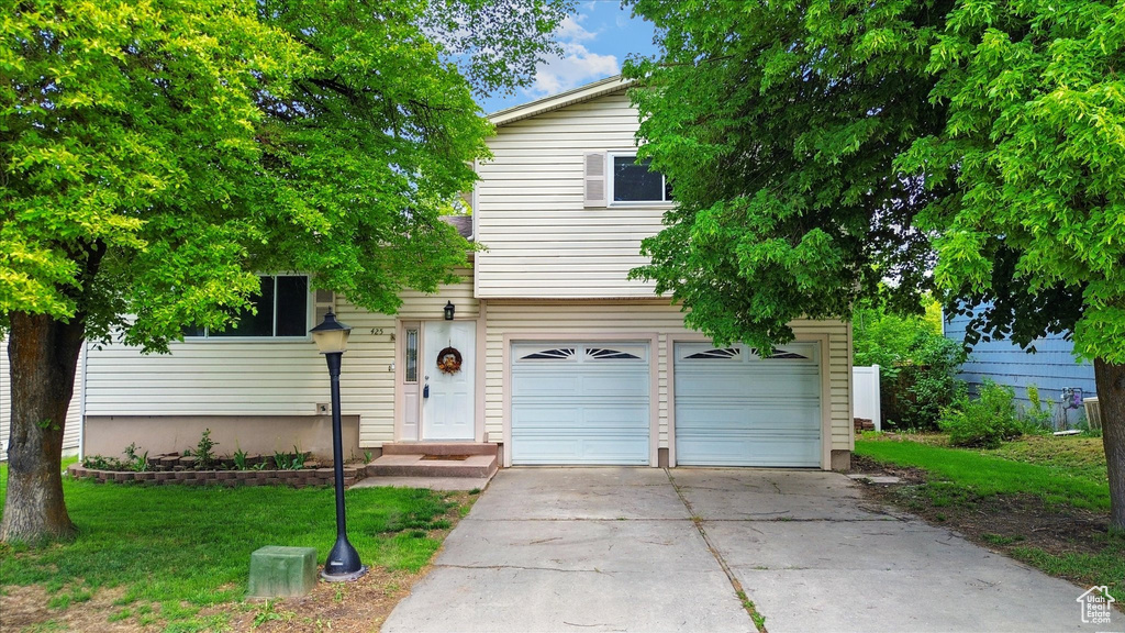 View of front of home featuring a garage, driveway, and a front yard