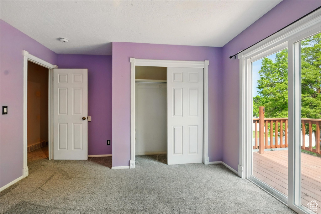 Unfurnished bedroom with access to exterior, carpet flooring, baseboards, and a closet