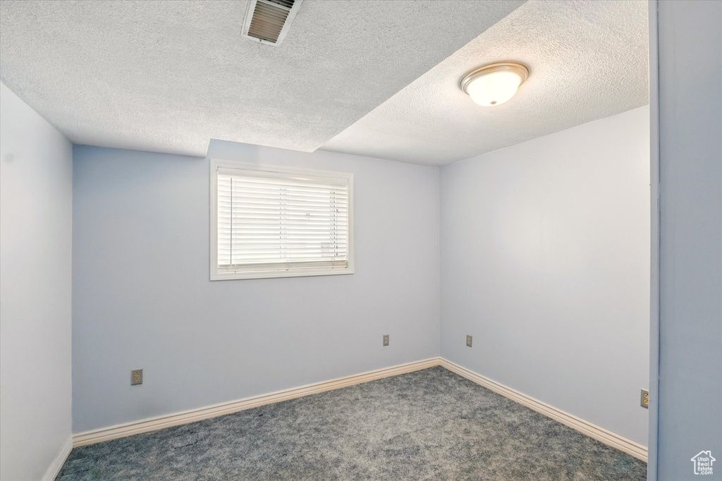 Unfurnished room with a textured ceiling, carpet floors, and baseboards
