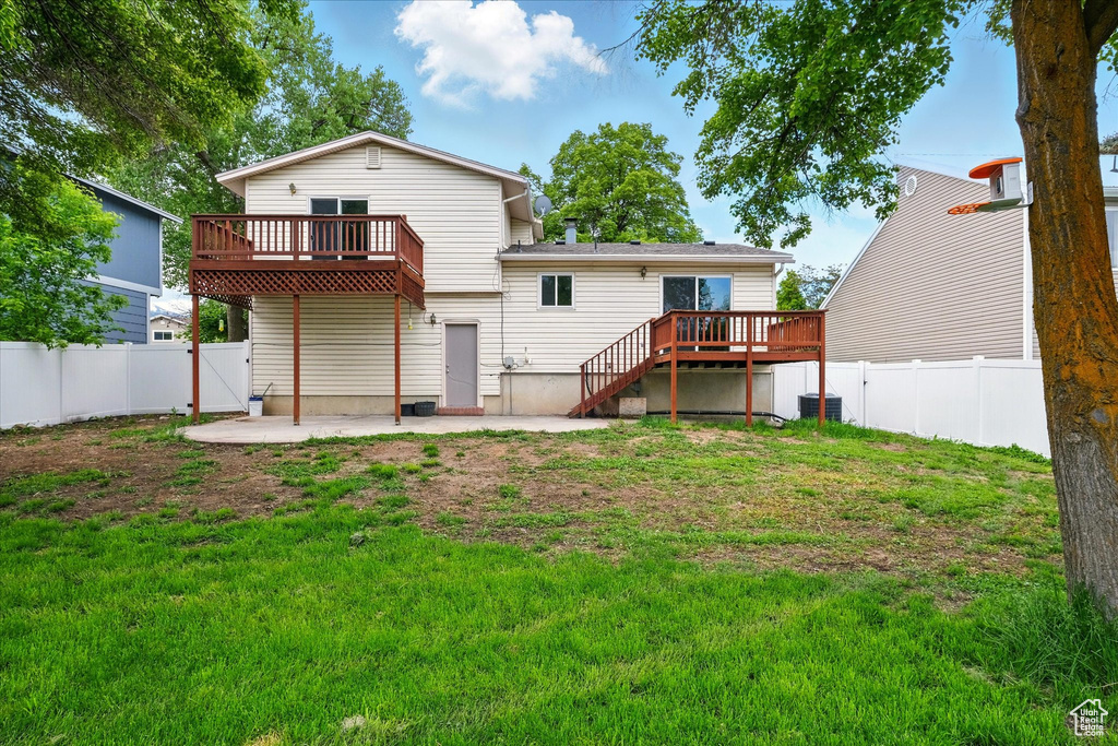 Back of property with a wooden deck and a patio