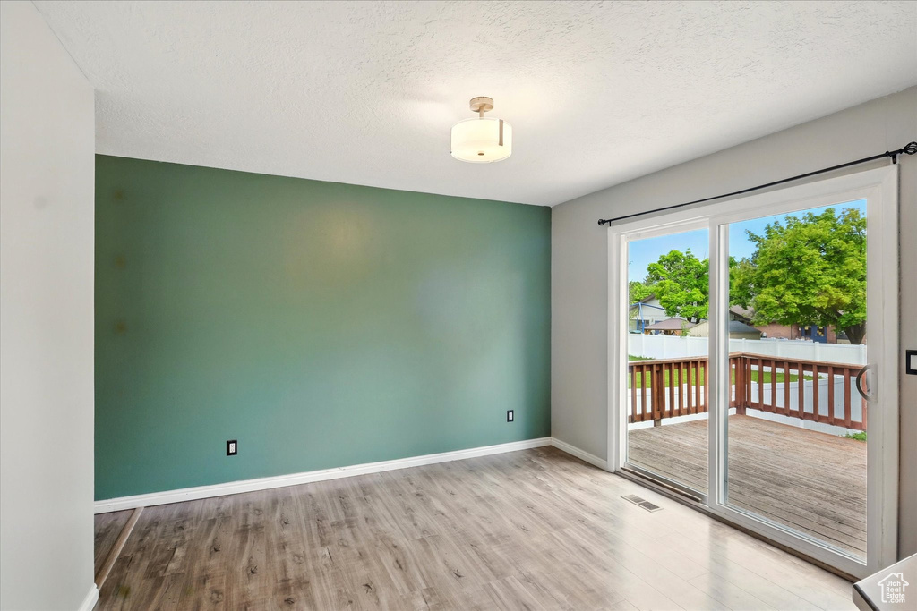 Empty room featuring wood finished floors, baseboards, and a textured ceiling