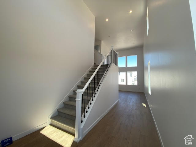 Staircase featuring wood finished floors and recessed lighting
