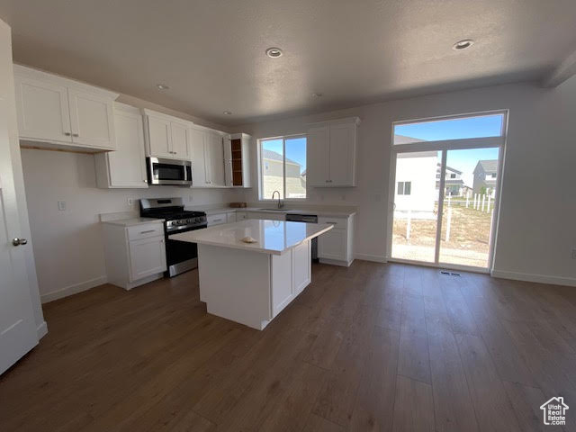 Kitchen with stainless steel appliances, white cabinetry, light countertops, a kitchen island, and recessed lighting