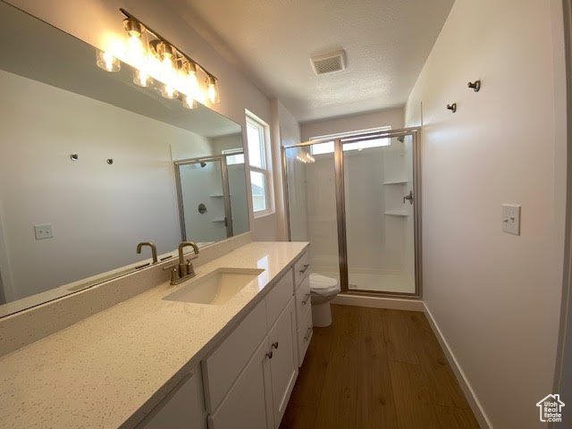 Full bathroom with vanity, a stall shower, and wood finished floors