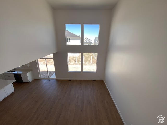 Unfurnished living room featuring healthy amount of natural light and dark wood-type flooring
