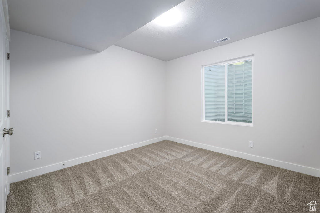 Carpeted spare room featuring baseboards