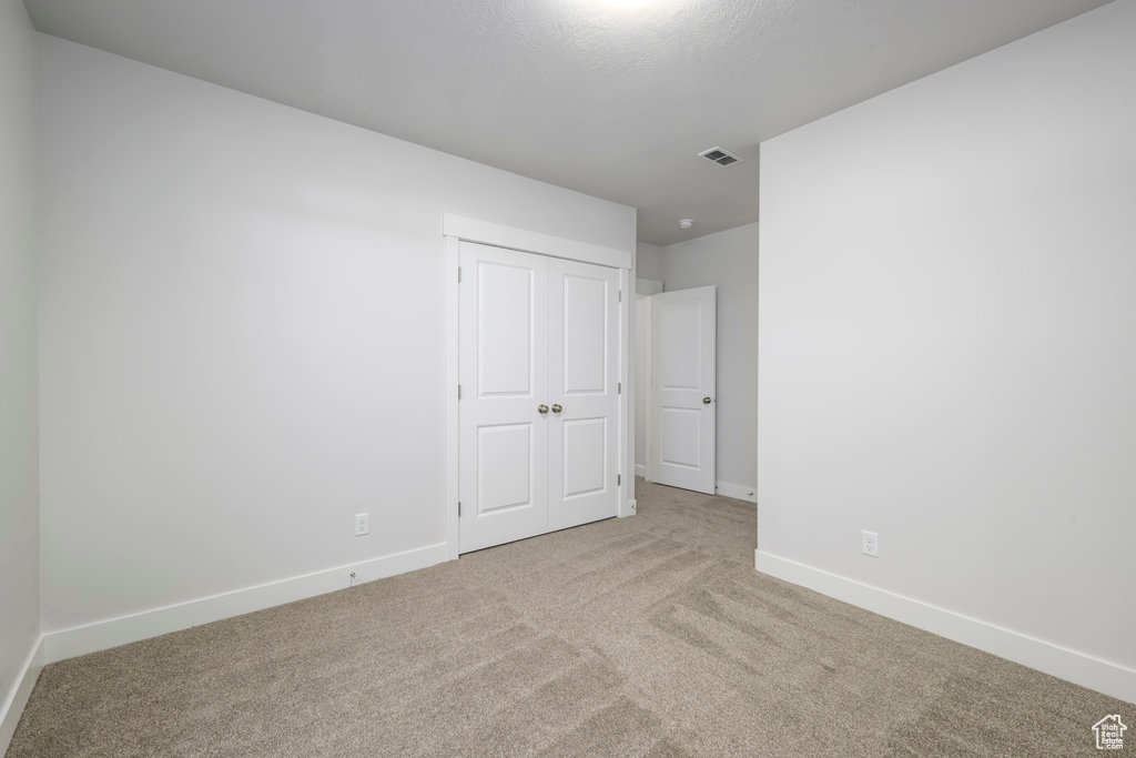 Unfurnished bedroom featuring carpet floors, baseboards, and a closet