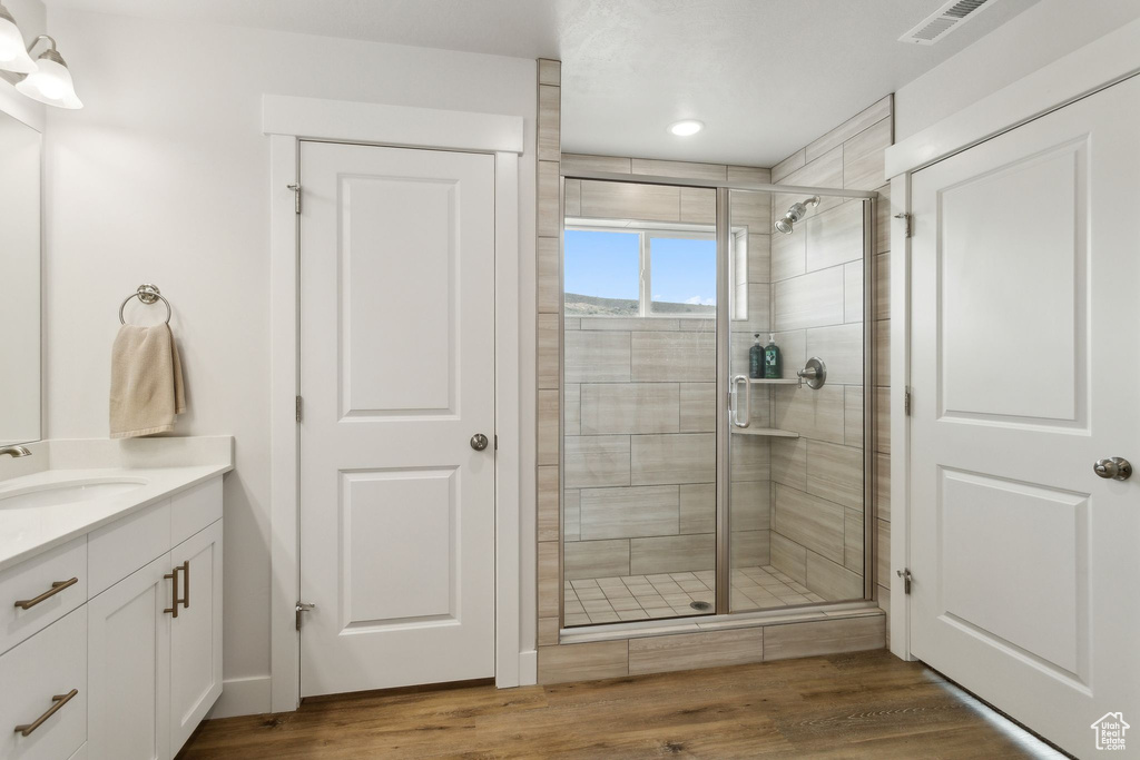 Full bathroom featuring a shower stall, vanity, wood finished floors, and recessed lighting
