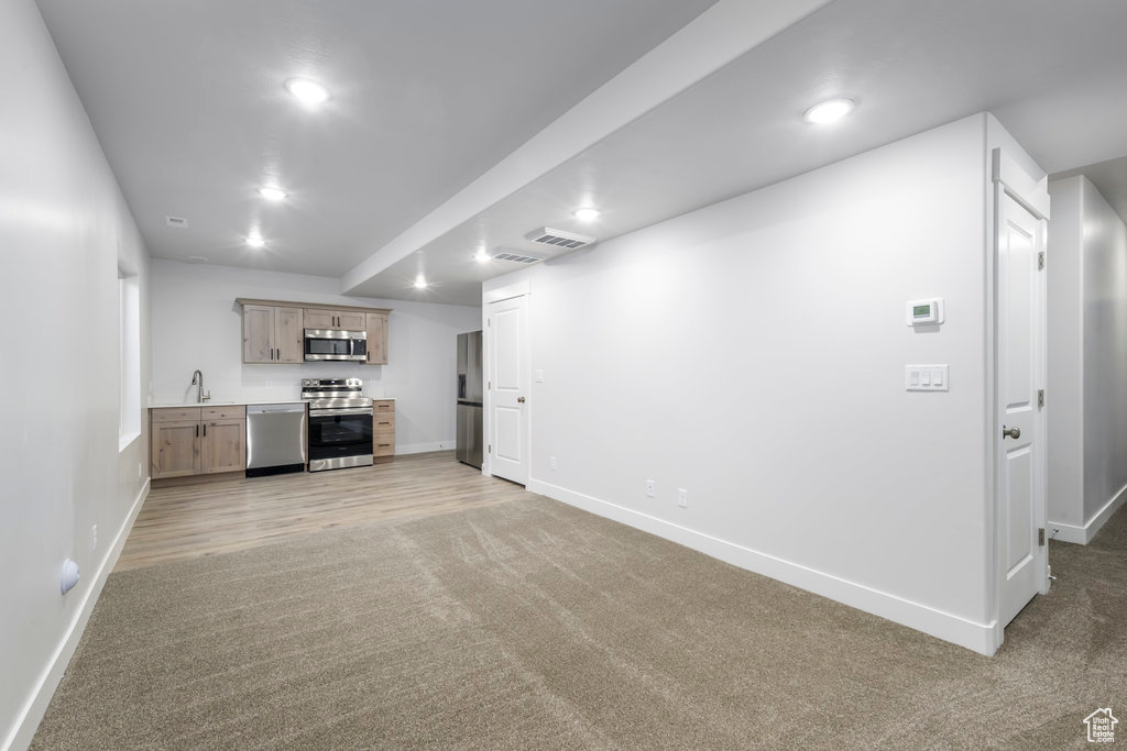 Unfurnished living room with baseboards, light carpet, bar with sink, and recessed lighting