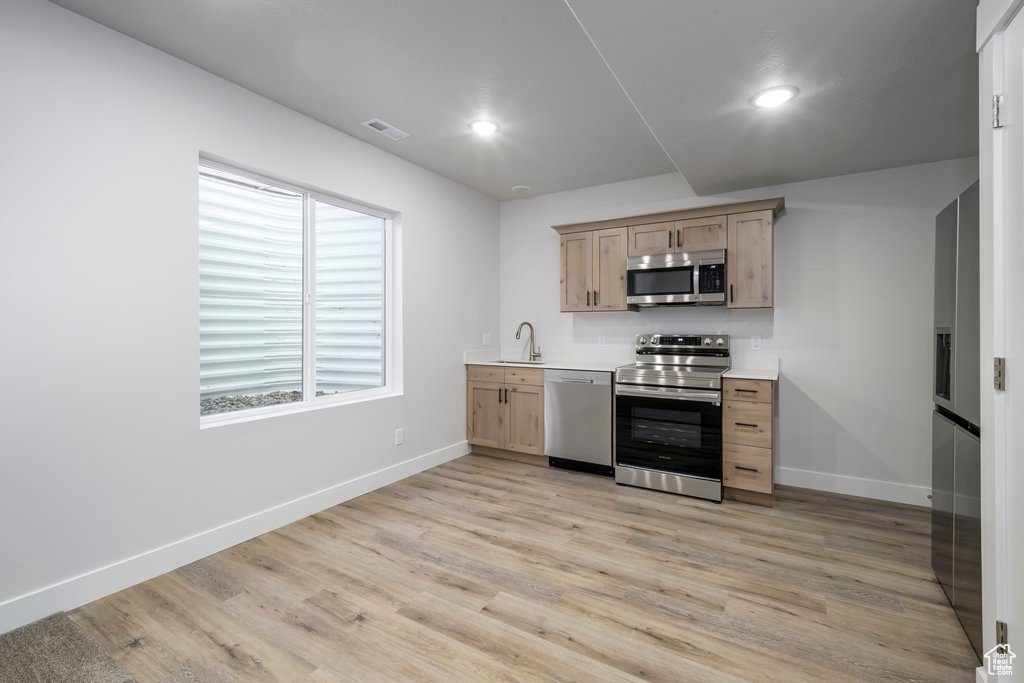 Kitchen featuring appliances with stainless steel finishes, light brown cabinetry, baseboards, light wood-style floors, and recessed lighting