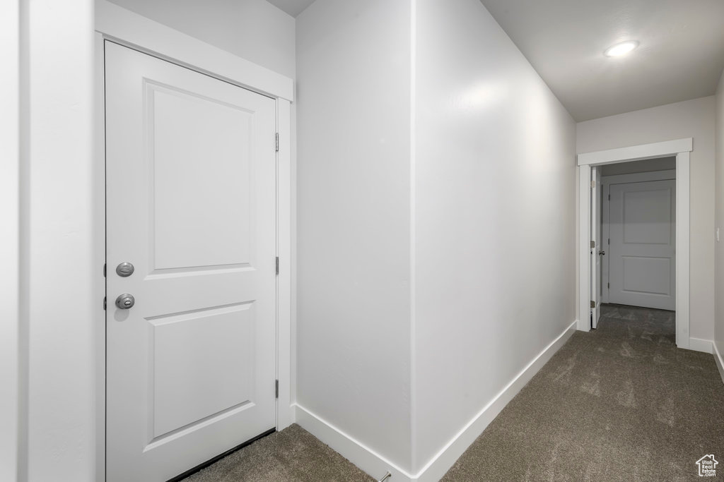 Corridor with dark colored carpet and baseboards