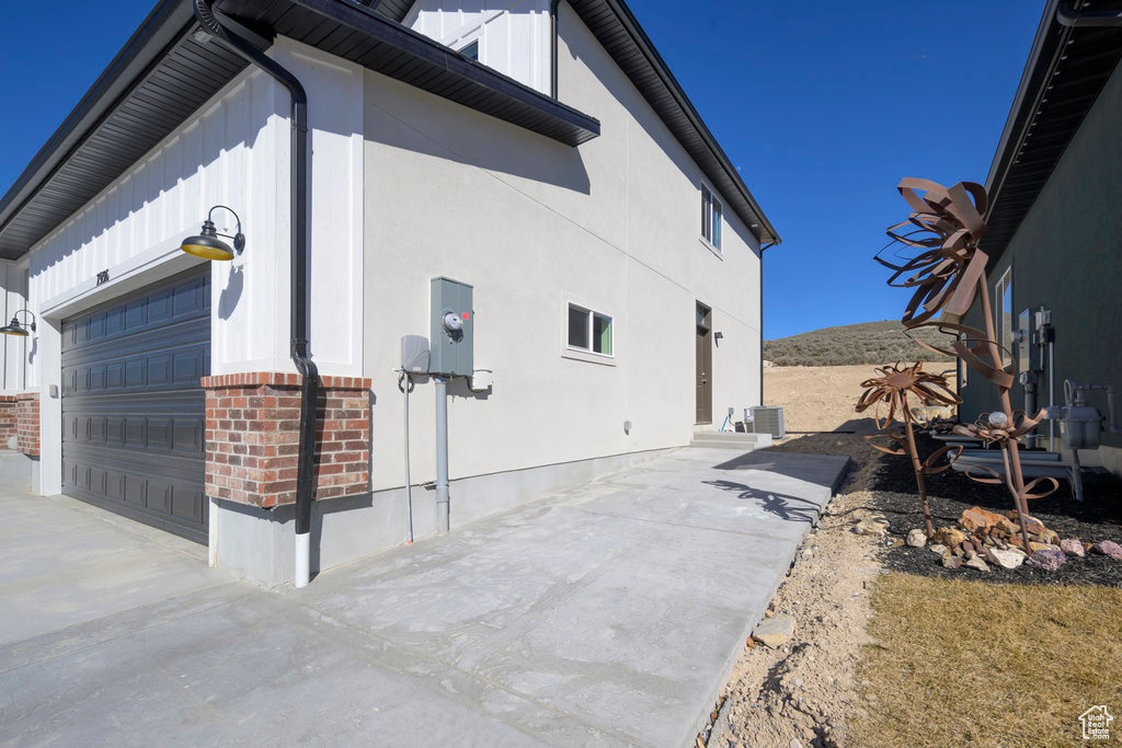 View of side of home featuring board and batten siding, brick siding, and concrete driveway