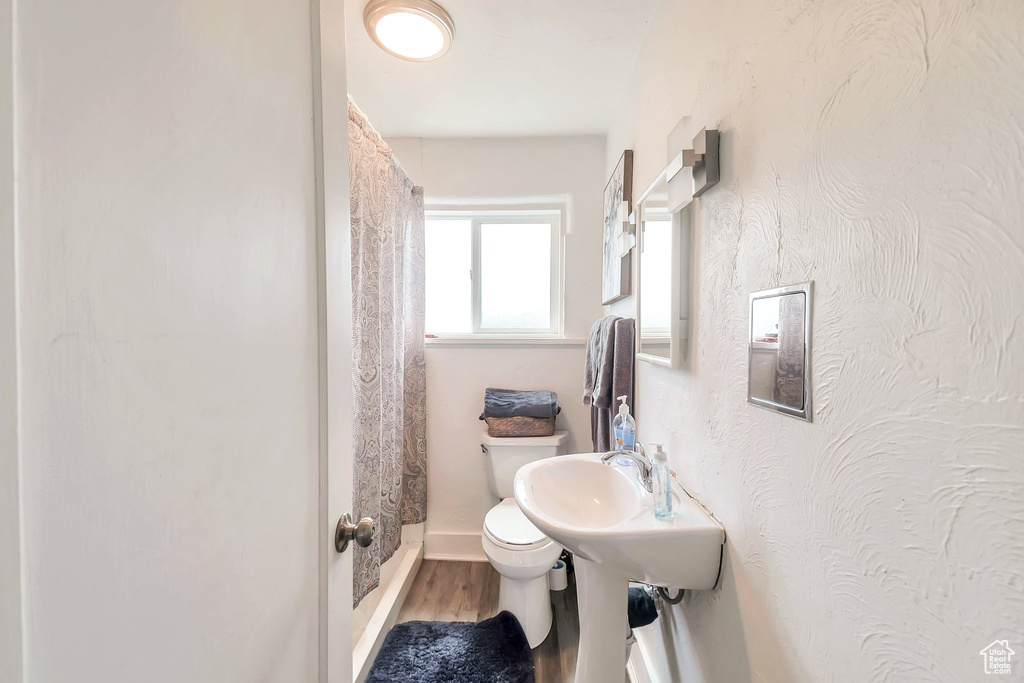 Full bathroom featuring toilet, wood finished floors, curtained shower, and baseboards