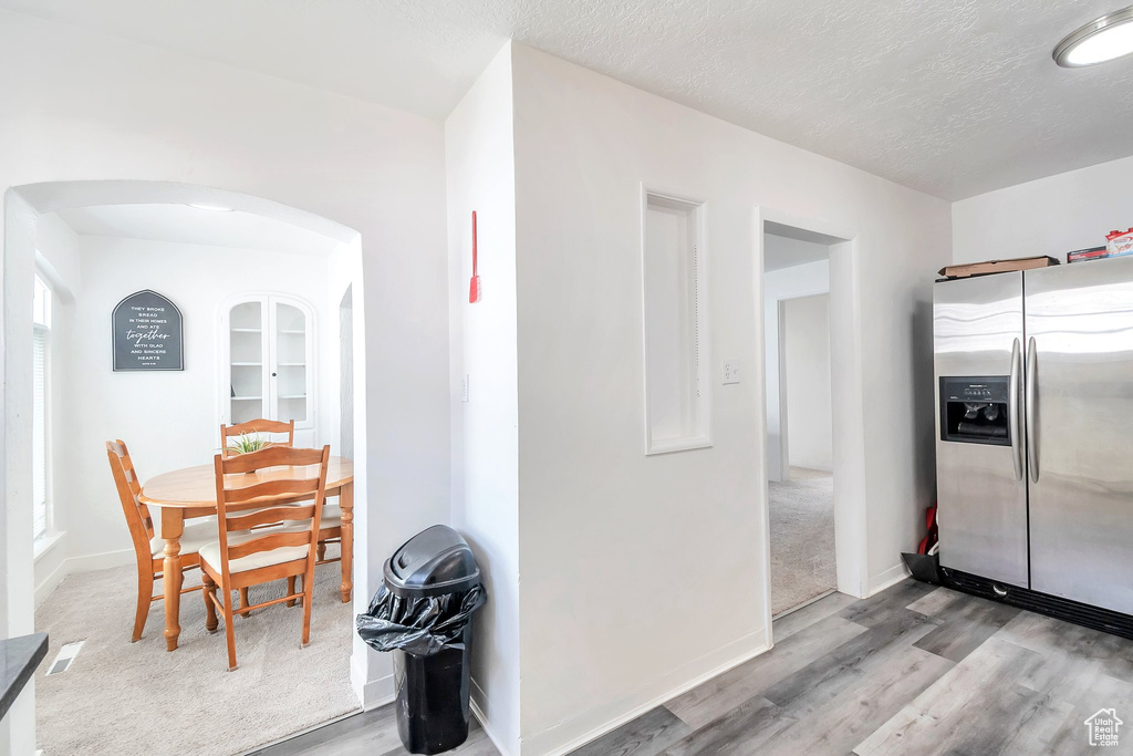 Dining space with arched walkways, wood finished floors, a textured ceiling, and baseboards