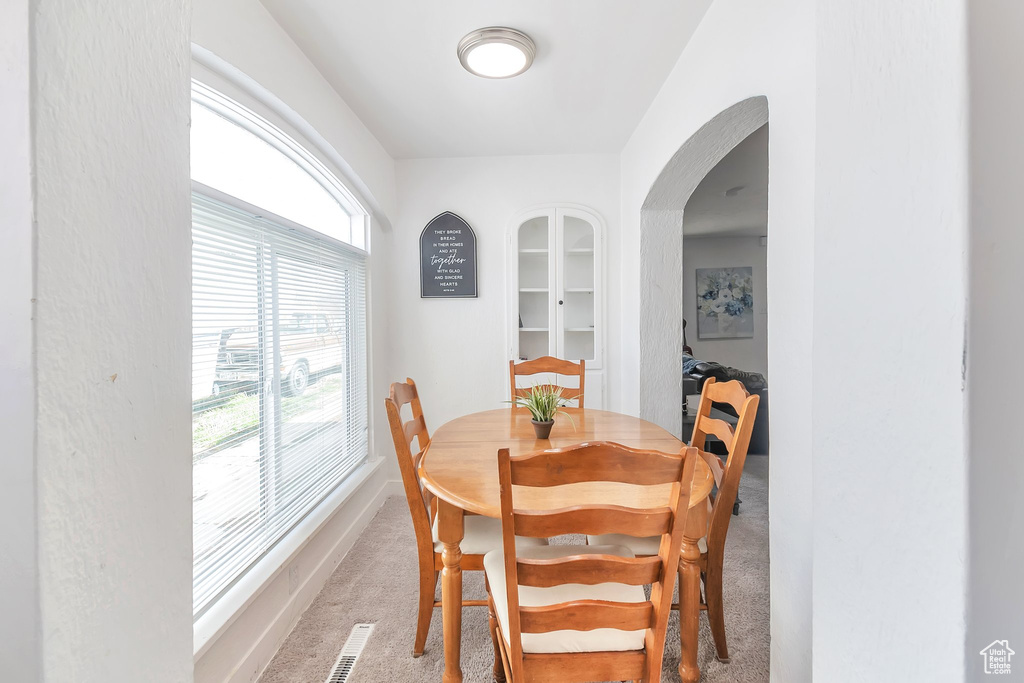 Carpeted dining room featuring arched walkways and baseboards
