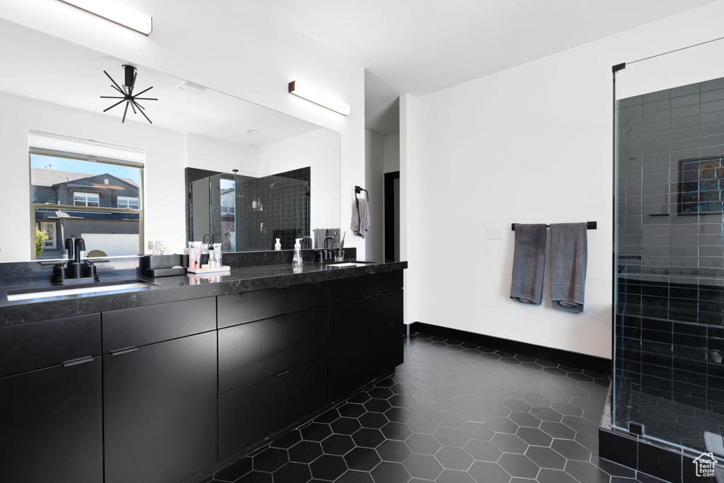Bathroom with double vanity, tiled shower, and tile patterned flooring