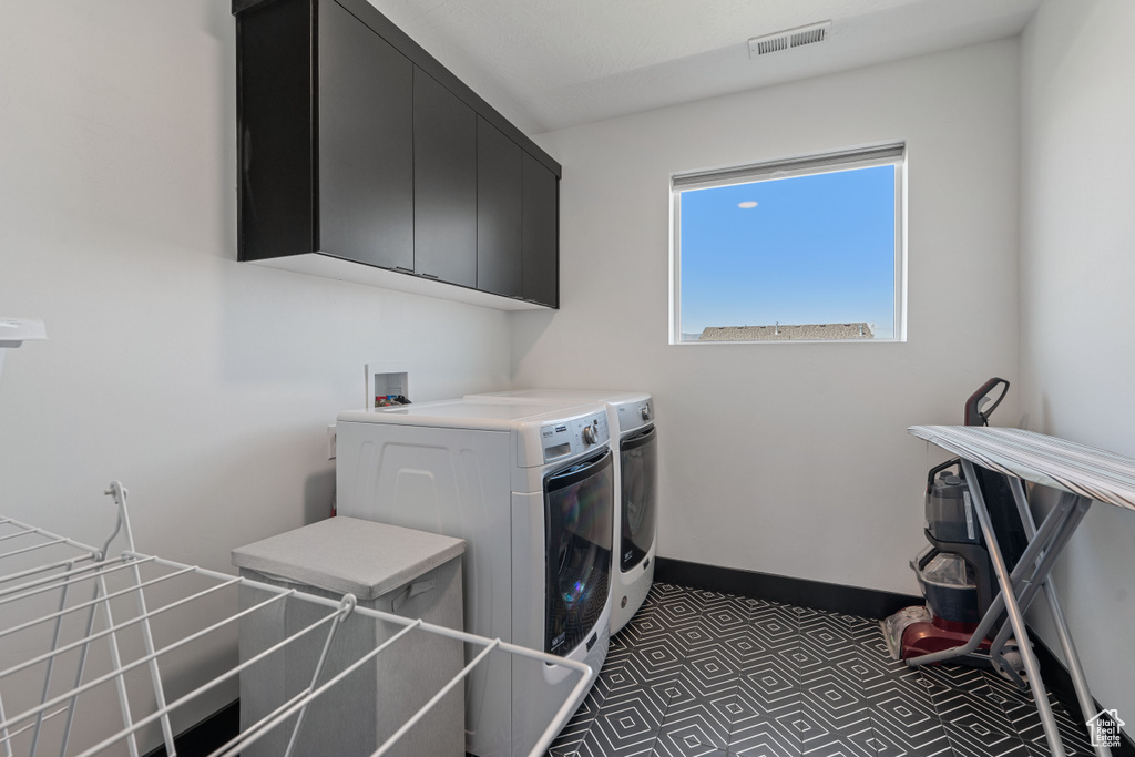 Laundry room with cabinet space, separate washer and dryer, tile patterned floors, and baseboards