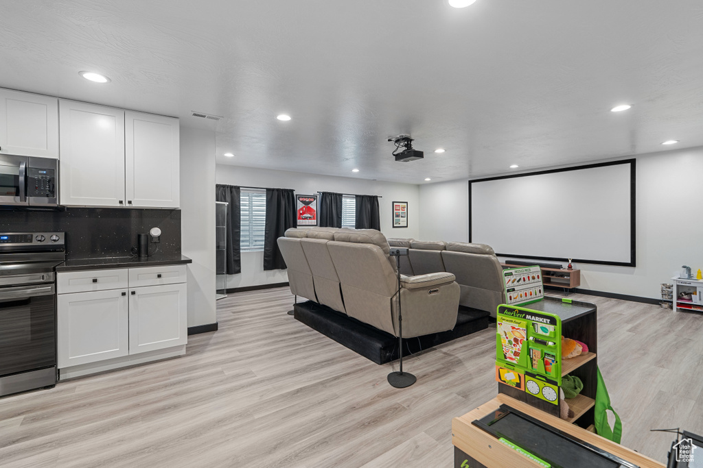 Home theater room featuring light wood-style flooring, recessed lighting, and baseboards