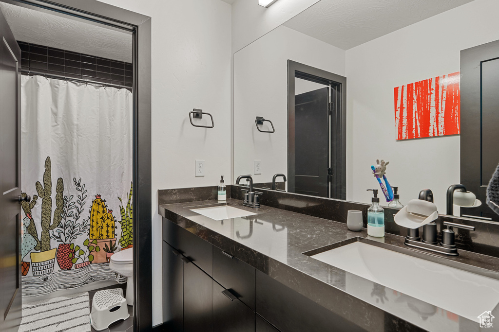 Full bathroom featuring toilet, double vanity, and a shower with curtain