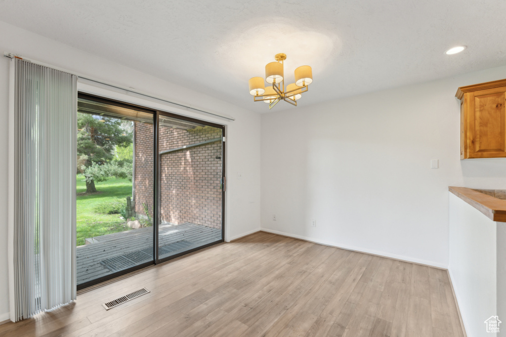 Unfurnished dining area featuring a chandelier, light wood-type flooring, baseboards, and recessed lighting