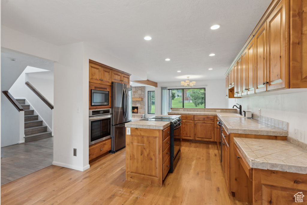 Kitchen with black appliances, a sink, light wood-type flooring, recessed lighting, and a center island