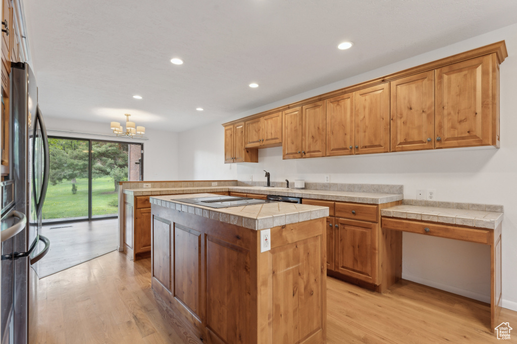 Kitchen featuring light wood-style floors, recessed lighting, a chandelier, freestanding refrigerator, and a peninsula