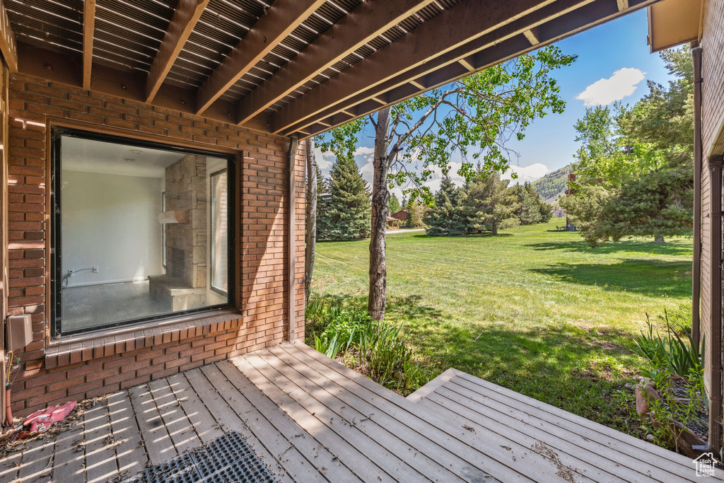 Wooden deck featuring a lawn and a mountain view